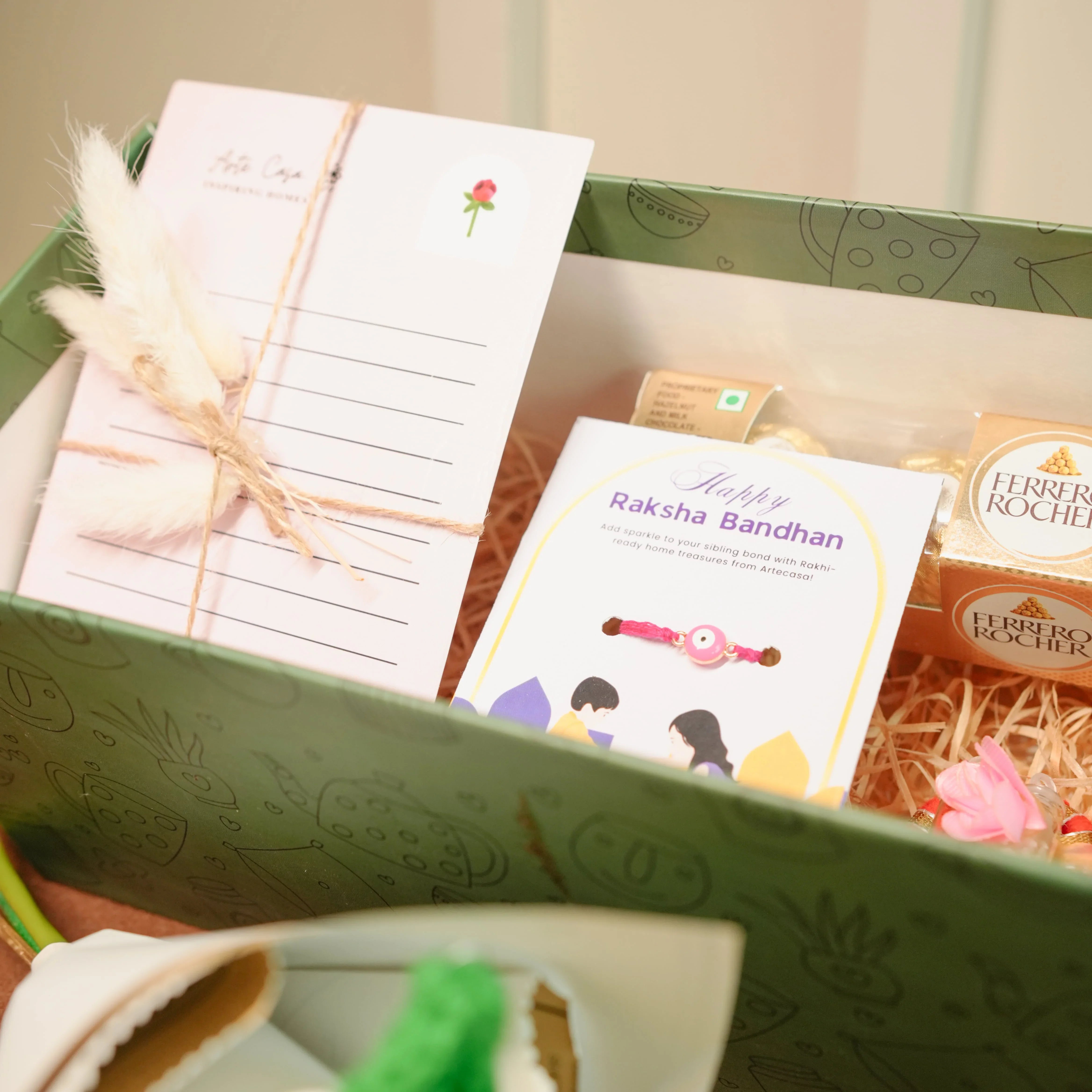 Flower-Themed Rakhi Hamper for Bhai & Bhabhi | Thoughtful Rakhi Gift Set with Candle, Chocolates & Flower Bunch