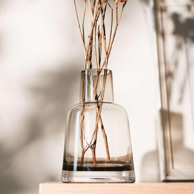 Clear glass vase with dried branches on a blurred background